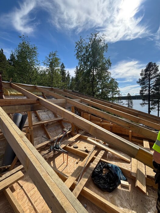 Takrenovering pågår, med synliga träreglar och takfot. Gamla taket är rivet, och isolering ska ökas från 120 mm till 340 mm.