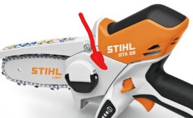Stihl GTA 26, orange och vit motorsåg, med röd pil som pekar på kedjans drivhjul och kåpa.