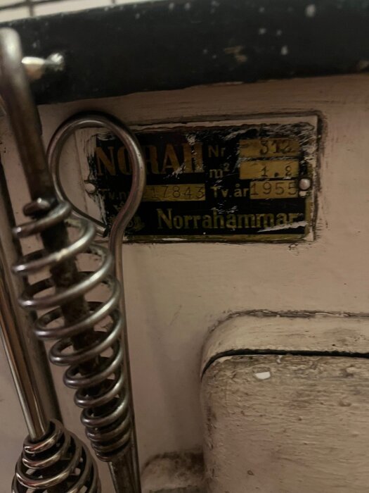Gammal märkplåt på värmepanna från Norrahammar med spiralfjädrar synliga till vänster.