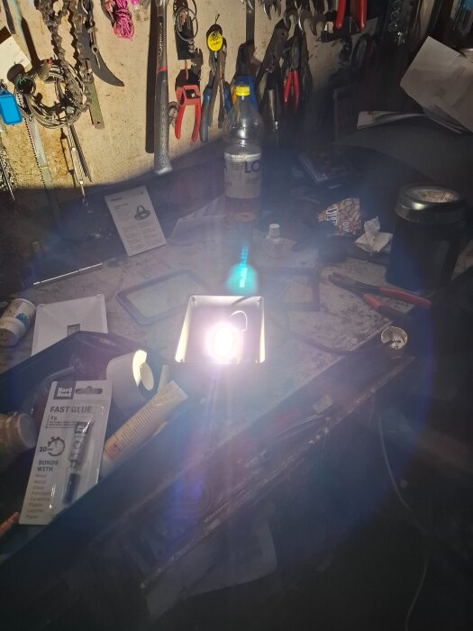 Arbetsbänk med verktyg och en påslagen lampa ovanpå. Verktygstavla i bakgrunden.