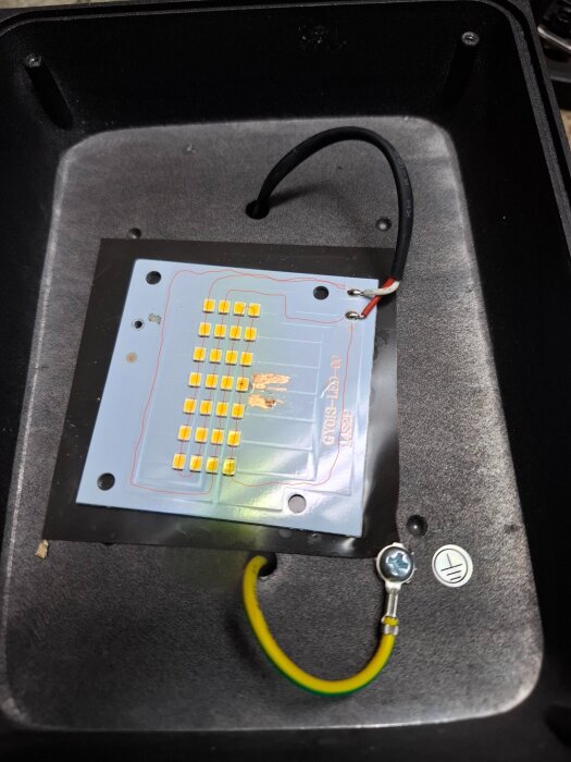 LED-panel monterad i en svart låda med kablar anslutna, varav en är gulgrön och jordad.