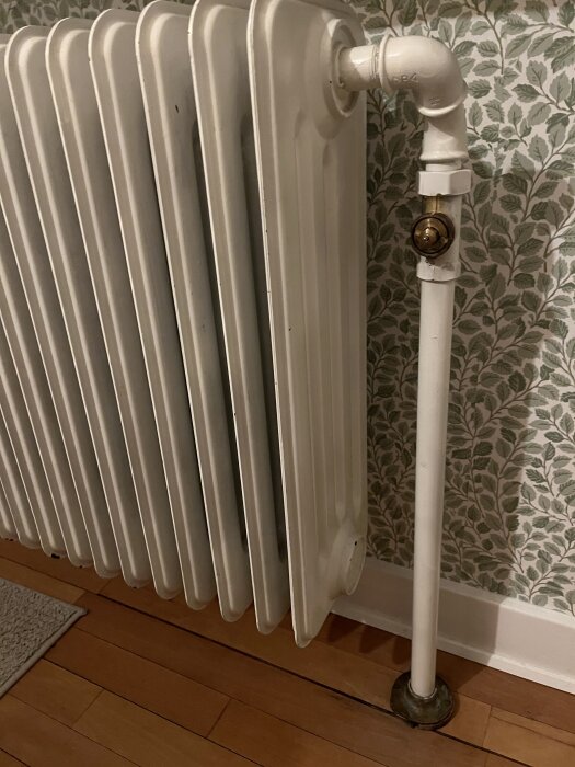 Gammalt vattenburet element i ett hus från 50-talet, delvis funktionsdugligt med ojämn värmespridning, luftventil synlig på sidan.