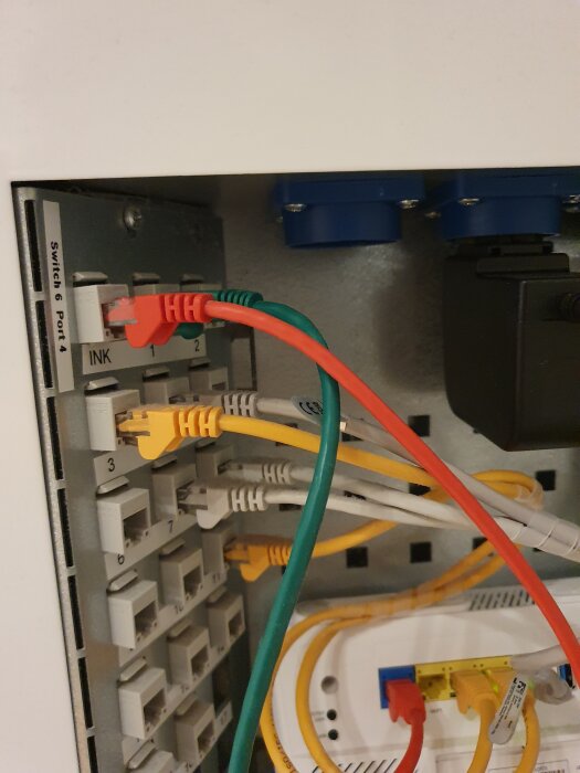 Nätverksskåp med flera ethernetkablar anslutna till en switch.