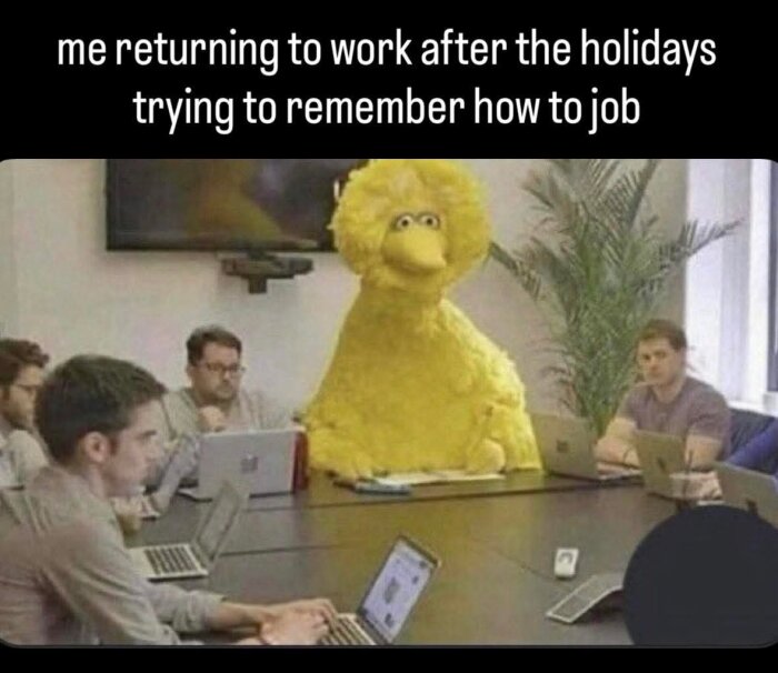 En gul, stor fågel sitter vid ett mötesbord med personer och datorer, text ovan "me returning to work after the holidays trying to remember how to job".