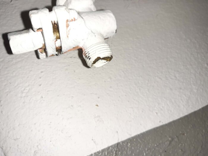 Radiatorventil på radiator C med vita och rostiga detaljer, indikerande dess anslutning i systemet.