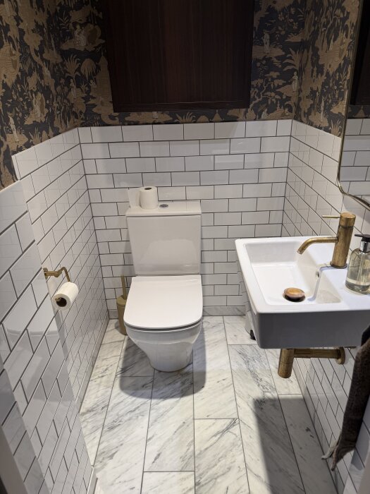 Toalett Duravit Starck 3 och handfat Duravit Vero i badrum med vita kakelväggar och mönstrad tapet.