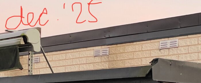 Bild på ett hus med nyligen installerade plåtar och en anteckning "dec '25" på väggen. Plåtarna verkar felmonterade enligt inläggstexten.