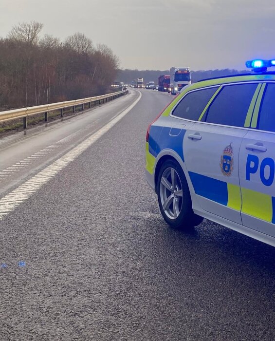 Polisbil på motorväg med blåljus, trafik i kö i bakgrunden, diskussion om korrekt användning av körfält.