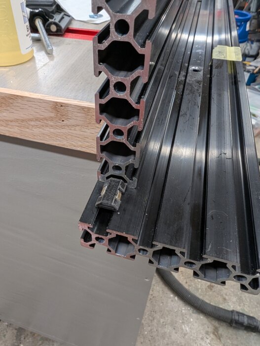 Aluminiumprofil monterad på ett fräsbord, med en liten T-mutter; en sugadapter och stödbitar för att hålla muttrarna på plats syns.