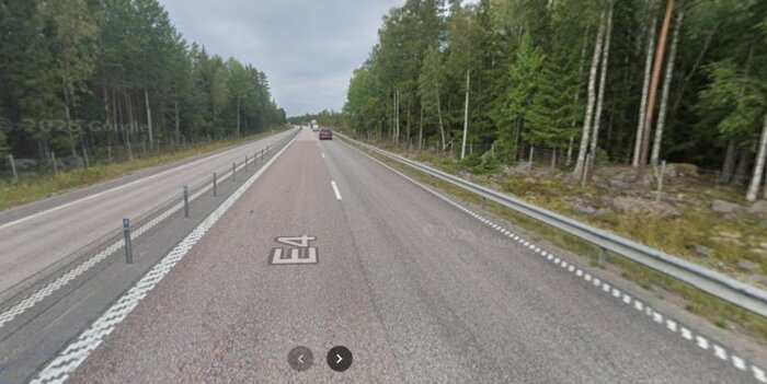 Motorvägen E4 genom skogsområde med två körfält i vardera riktningen och mitträcken.