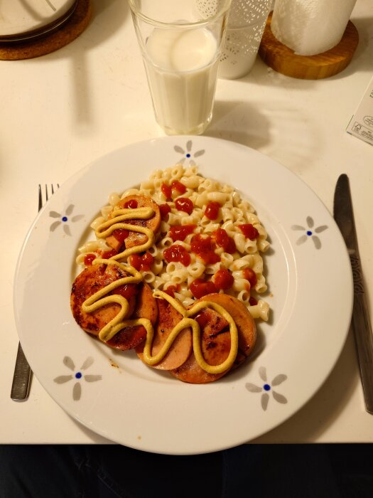 Tallrik med stuvade makaroner och skivad falukorv, toppad med ketchup och senap. Glas mjölk intill.
