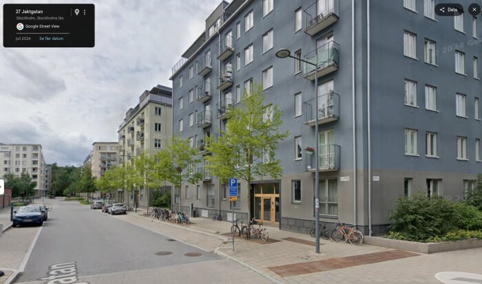 Flerfamiljshus längs en gata i Stockholm med cyklar parkerade utanför.