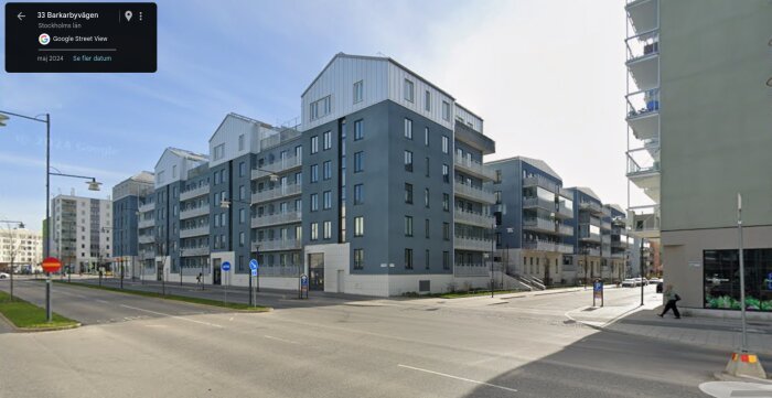 Nya bostadshus i ett område i Stockholm, med moderna arkitektoniska drag och grå fasader, bredvid en gatuvy.
