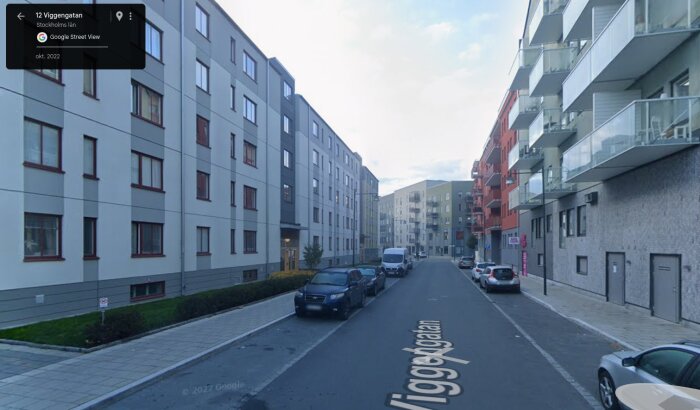 Gata med moderna flerbostadshus på båda sidor, parkerade bilar längs trottoarerna och tydlig gatutext "Viggegatan".