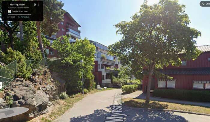 Vägbild från Stockholm-förort med moderna flerfamiljshus och träd. Solig dag vid Myrstuguvägen, Huddinge.