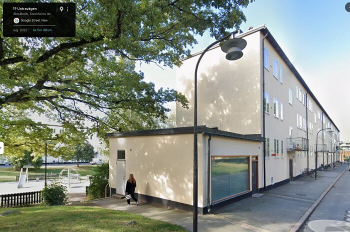 Gatulandskap i Stockholmsförort med moderna byggnader, cyklar och en kvinna som går på trottoaren, typisk för vardagsmodernism.