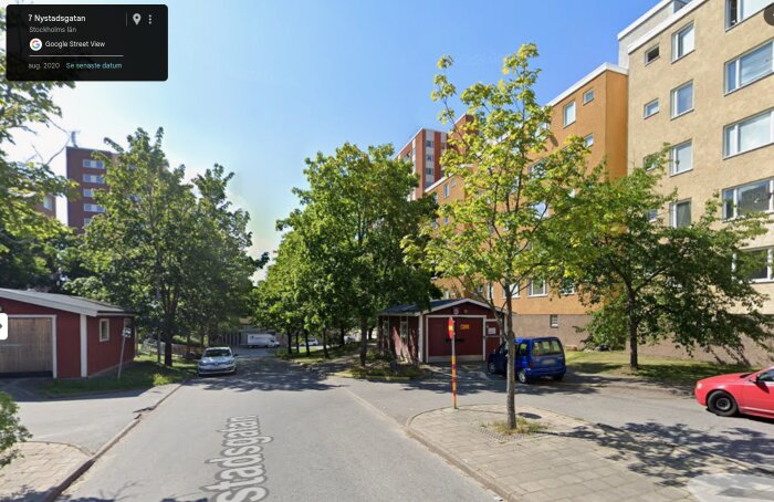 Stockholmsförort med modernistiska byggnader, grönskande träd och parkerade bilar på en lugn gata med blå himmel.