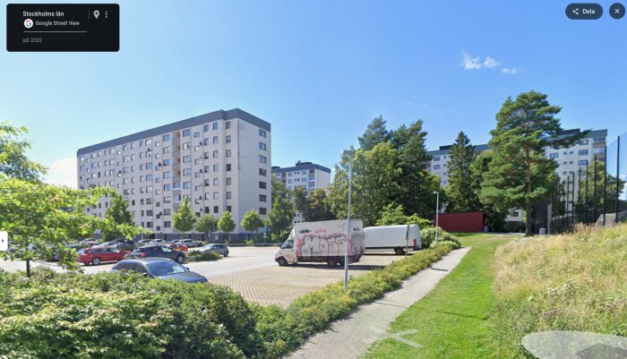 Flervåningshus i modern stil i Stockholms förorter, omgivna av bilar, grönska och träd en solig dag.