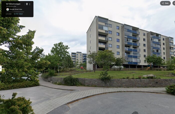 Bostadshus i modernistisk stil i en Stockholmsförort, omgivna av grönska och trottoarer.
