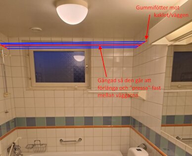 Gängbar torkställning mellan väggar i ett kaklat badrum, markerad med röda stänger och blå linor, med instruktioner för montering utan att skada väggen.