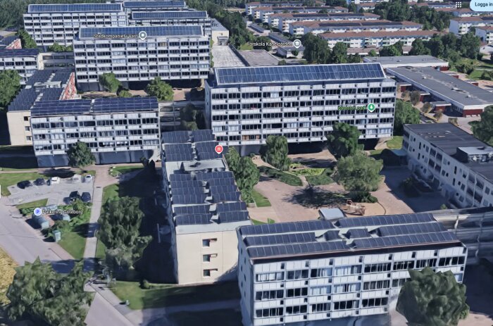 Flerbostadshus med solpaneler på taken, omgivna av grönska och gångvägar i en stadsdel med flera byggnader i närheten.