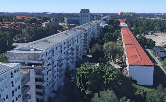 Flygbild över flerbostadshus med vita och röda tak i ett grönområde, med etiketter för Gårdstens Centrum och Kvibergs Vandrarhem.