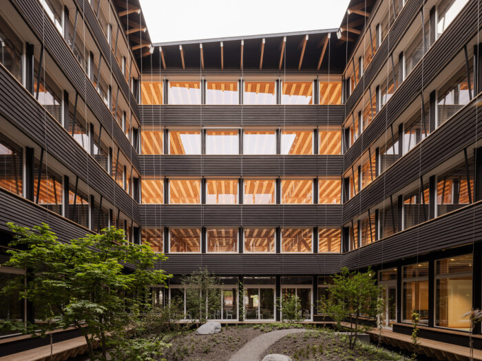 Ett modernt fyrkantigt innergård med trädetaljer och stora fönster som del av Herzog & de Meurons Hortus-projekt.