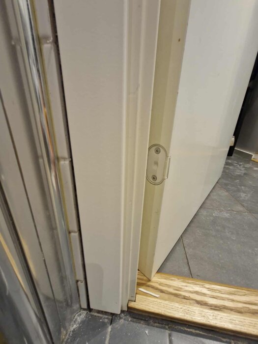 Närbild på dörrfoder och tröskel i ett badrum, visar området där silikonfogen varit otillräcklig och orsakat röta i materialet.