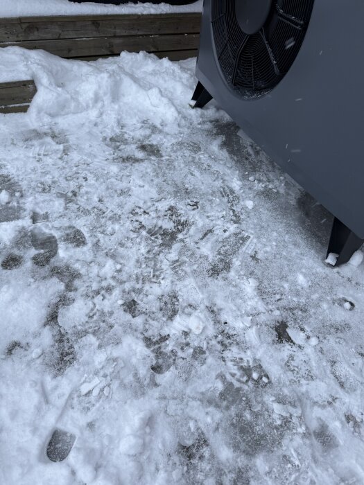 Isbildning framför en CTC-värmepump med synlig fläkt; snö och is på marken.