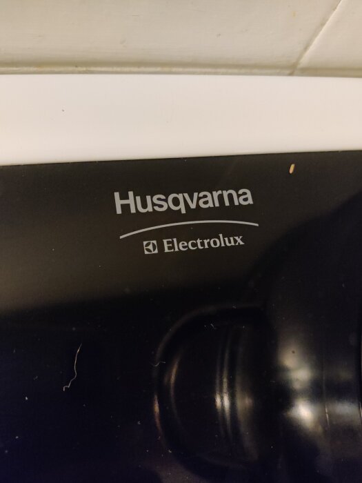 Bild på ett svart hushållsapparat från Husqvarna Electrolux, med logotyp synlig ovanför en ratt.