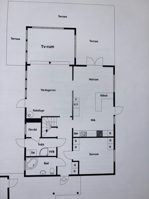 Planlösning av ett 70-tals hus, visar rum som tv-rum, matsal, kök, sovrum och bad, med detaljer som kakelugn och terrass.