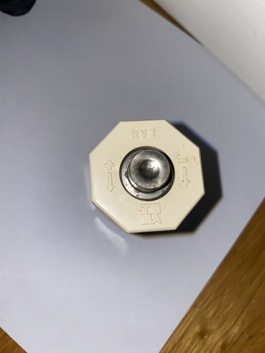 En vit ratt från en äldre värmeregulator med texten "RVT" och pilar som visar riktningar, sannolikt från tidigt 70-tal.