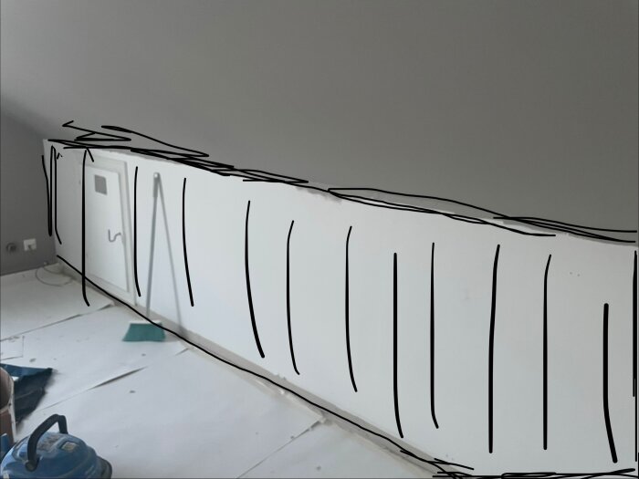 Sovrum under renovering med snedvägg, dörr till kattvind och planer på akustikpanel. Dörren sticker ut och list runt ska tas bort.