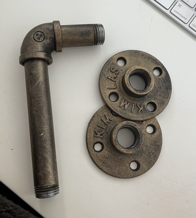Industridesignade hyllkonsoler i metall, mörk finish, del av ett väggmonteringsprojekt för högtalare, med skruvhål och texten "KIM LAS".