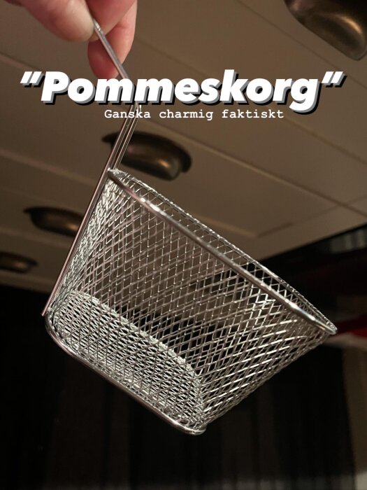 Trådkorg för pommes frites visas upp mot en bakgrund med köksskåp.