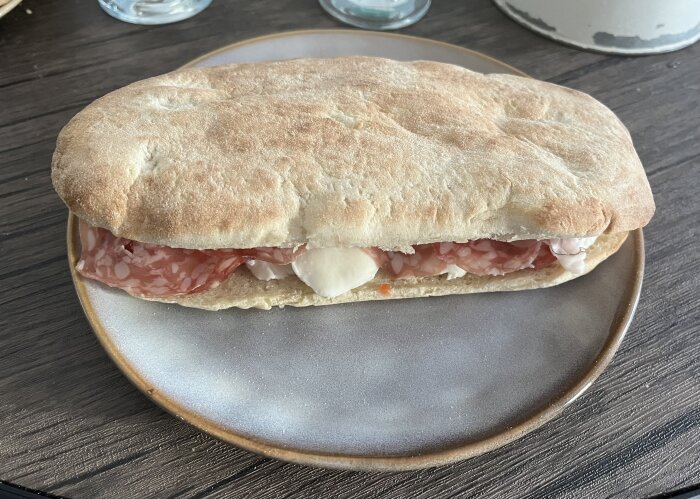 Italiensk macka med salami, mozzarella och serranoskinka på fat.