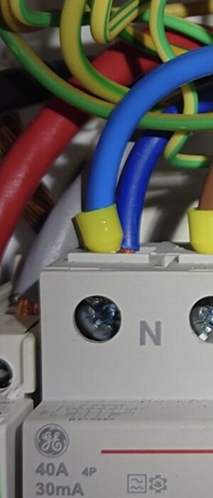 Flera färgade elkablar anslutna till en strömbrytare med märkningen 40A och 30mA, inklusive en mångtrådig blå kabel.