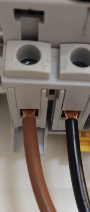 Brun och svart mångtrådig kabel ansluten till en grå kopplingsplint.