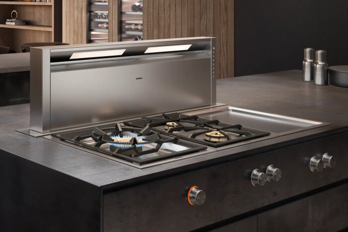 Gashäll och köksfläkt från Gaggenau i ett modernt kök, med en låga på en av brännarna.