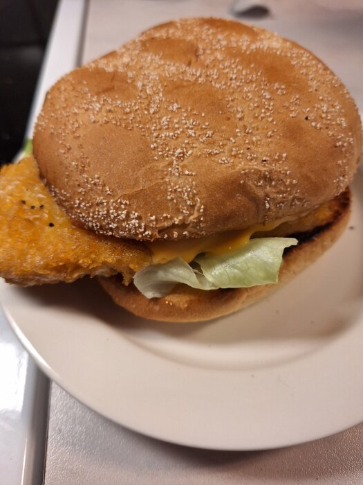 Vegoschnitzel i hamburgerbröd med sallad och ost på en tallrik.