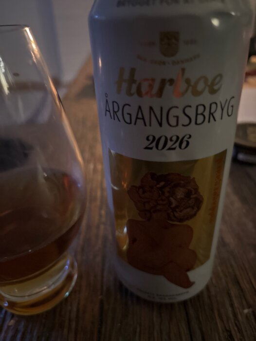 Burk av Harboe Årgångsbryg 2026, en imperial pilsner, bredvid ett glas med dryck på ett bord.