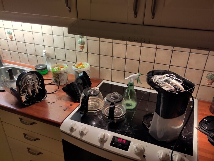 Delad värmeelementenhet från en kaffemaskin med köksredskap och skräp i bakgrunden på en diskbänk.