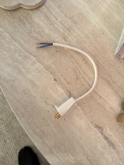 Vit lampkontakt med två exponerade kablar på ett bord, förberedd för installation av taklampa.