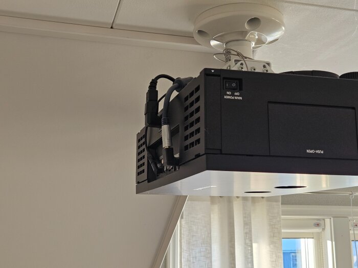 Väggmonterad bioprojektor med vinkeladaptrar på kablar i trapphusets övervåning, förbättrad kabeldiskretitet.