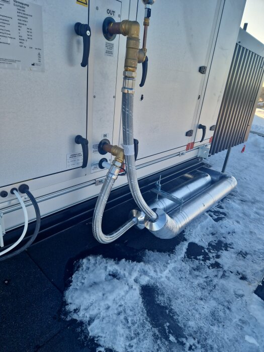 Isolerade värmebärarrör monterade på tak med synlig snö, visar installation i kall utomhusmiljö.