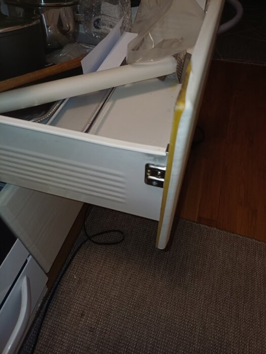 Öppen kökslåda med skrynklig folie, intilligande ugn och köksartiklar. Folien har blivit vågig av ugnens värme.