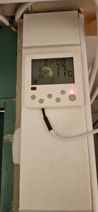 Termostat med felmeddelande "Er08" och temperaturvisning på 11°C, ansluten med en kabel i en hemmiljö.