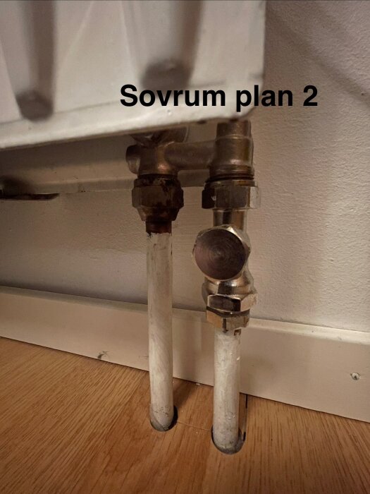 Radiator med strypventil i sovrum på plan 2, två kopparrör anslutna under, monterad på trägolv med vita golvlister.