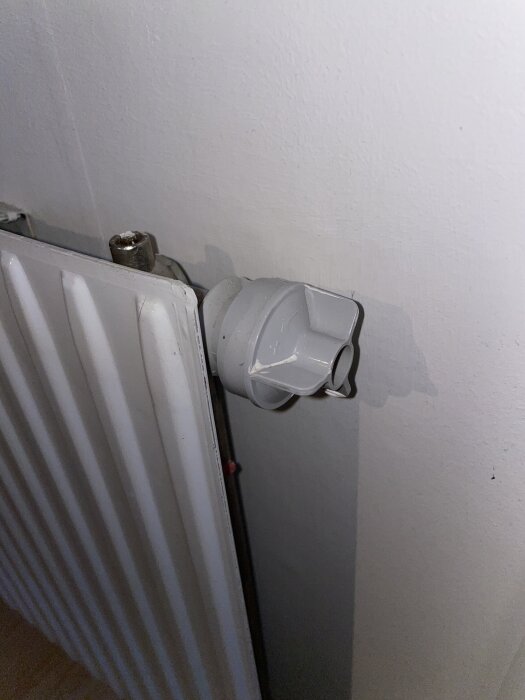 Radiator med en justeringsventil utan termostat, sett från sidan monterad mot en vägg.