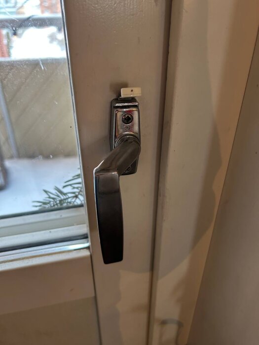 Handtag på balkongdörr med barnspärr i vit lägenhet.